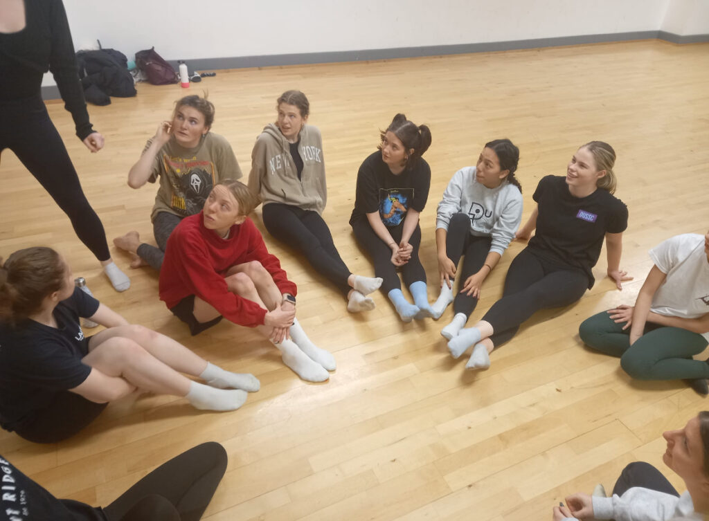 Dancers sitting on the floor in a semi-circle